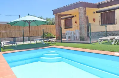 a pool in front of a house with an umbrella at Chalet Bella Mendoza in Conil de la Frontera