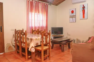 a living room with a table and chairs and a television at Chalet Bella Mendoza in Conil de la Frontera