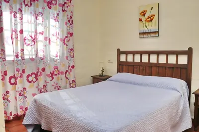 a bedroom with a bed and a window with curtains at Chalet Bella Mendoza in Conil de la Frontera