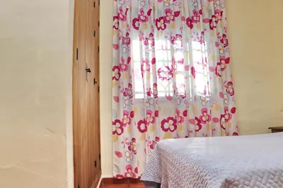 a bedroom with a window with pink and white curtains at Chalet Bella Mendoza in Conil de la Frontera