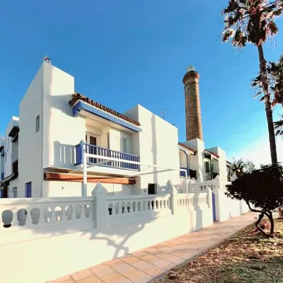 a white house with a lighthouse in the background at Casa mirando al mar, hermosas vistas. in Chipiona