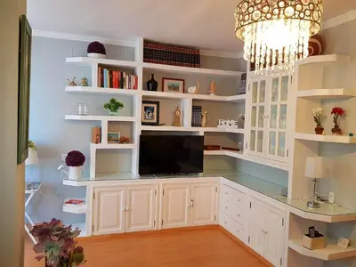 a large kitchen with white shelves and a television at APARTAMENTO CORTADURA BEACH in Cádiz
