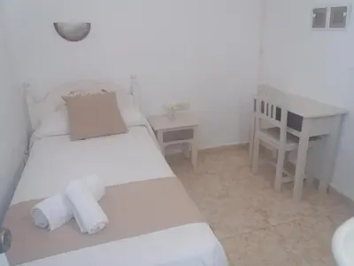a white bedroom with a bed and a desk at Hospederia Islasol in San Fernando