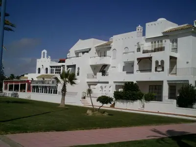 a large white building with a palm tree in front of it at Primera linea de playa 