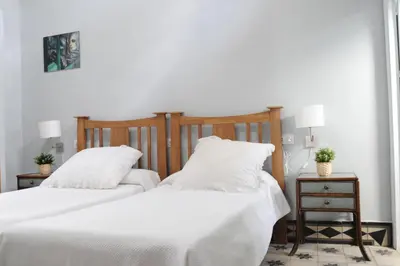 two beds in a bedroom with white sheets and pillows at Casa de Lys in Sanlúcar de Barrameda