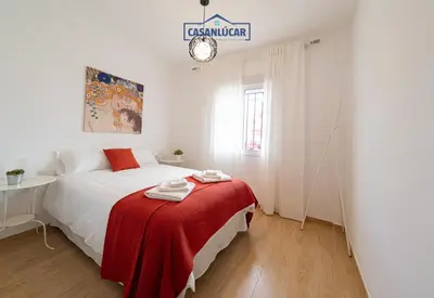 a white bedroom with a bed with a red blanket at Parque Doñana in Sanlúcar de Barrameda