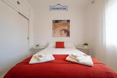 a bedroom with a red and white bed with two towels at Parque Doñana in Sanlúcar de Barrameda