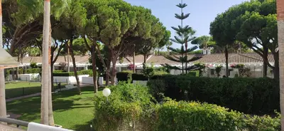 a garden with trees and bushes and a building at Apartamento la Barrosa ,Urb los Veleros in Chiclana de la Frontera