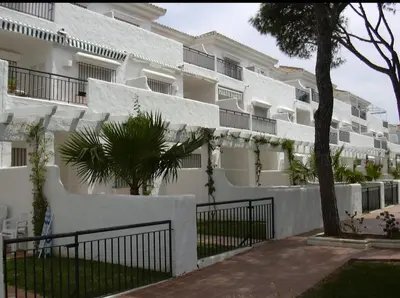 a white building with a fence in front of it at Apartamento la Barrosa ,Urb los Veleros in Chiclana de la Frontera