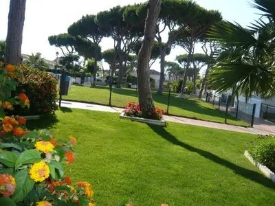 a park with palm trees and flowers in the grass at Apartamento la Barrosa ,Urb los Veleros in Chiclana de la Frontera