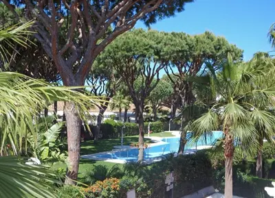 a swimming pool surrounded by trees and plants at Apartamento la Barrosa ,Urb los Veleros in Chiclana de la Frontera