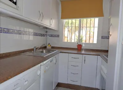 a kitchen with white cabinets and a sink and a window at Apartamento la Barrosa ,Urb los Veleros in Chiclana de la Frontera