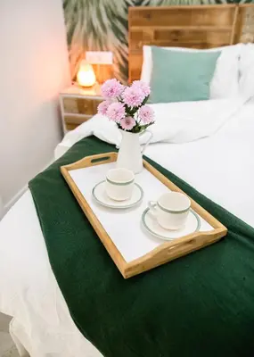 a tray with two cups and a vase with flowers on a bed at innCádizCASA SEÑORIAL DE 1790 in Cádiz