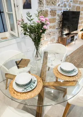 a glass table with two chairs and a vase with flowers at innCádizCASA SEÑORIAL DE 1790 in Cádiz
