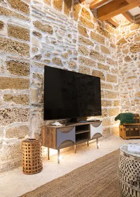 a living room with a tv on a stone wall at innCádizCASA SEÑORIAL DE 1790 in Cádiz