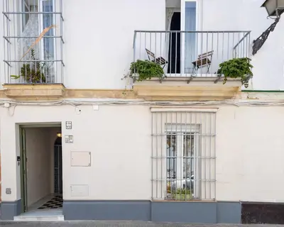 a white building with a balcony with plants on it at Casa Portus Gaditanus s XVIII Patio Andaluz in El Puerto de Santa María