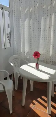 a white table and chairs and a vase with a flower on it at Casa Mercedes in Rota