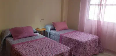 two beds with pink and purple covers in a room at Casa Mercedes in Rota
