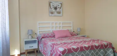a bedroom with a bed with a pink and gray comforter at Casa Mercedes in Rota