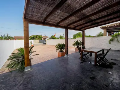 a patio with a table and chairs and a roof at Chalet Conil Ramirez in Conil de la Frontera