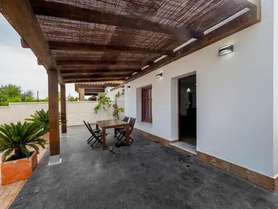 a patio with a table and chairs next to a building at Chalet Conil Ramirez in Conil de la Frontera