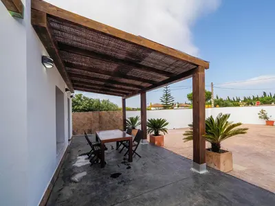 a patio with a wooden pergola with a table and chairs at Chalet Conil Ramirez in Conil de la Frontera