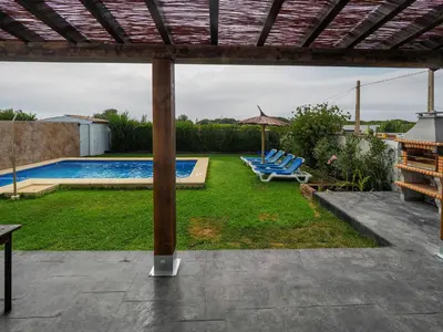 a yard with lounge chairs and a swimming pool at Chalet Conil Ramirez in Conil de la Frontera