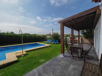 a patio with a table and chairs next to a swimming pool at Chalet Conil Ramirez in Conil de la Frontera