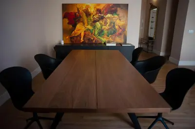 a wooden table with chairs in a room with a painting at Casa Plaza de las Flores Cádiz Grupo AC Gestión in Cádiz
