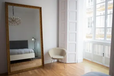 a mirror in a room with a chair and a bed at Casa Plaza de las Flores Cádiz Grupo AC Gestión in Cádiz