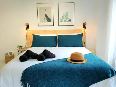 a bed with a blue blanket and a hat on it at Sherryflat Jarana- Parking in Jerez de la Frontera