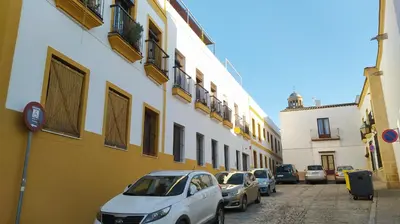 a row of cars parked on a street next to buildings at Sherryflat Jarana- Parking in Jerez de la Frontera