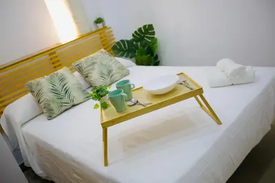 a white bed with a wooden tray on top of it at Loft CENTRO San Diego in Sanlúcar de Barrameda