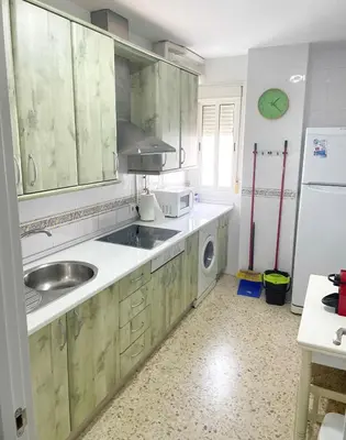 a kitchen with wooden cabinets and a sink and a dishwasher at Azvalia - Valparaíso beach apartment - Piscina y parking gratis in El Puerto de Santa María
