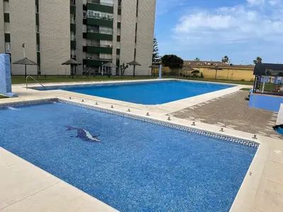 a large pool with blue water in front of a building at Azvalia - Valparaíso beach apartment - Piscina y parking gratis in El Puerto de Santa María