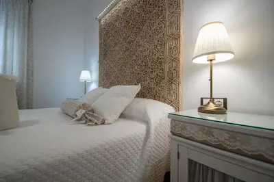 a bedroom with a bed with a headboard and a lamp at Apartamento Garum in Cádiz