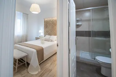 a bedroom with a bed and a bathroom with a shower at Apartamento Garum in Cádiz