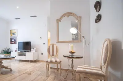 a living room with a table and two chairs and a mirror at Apartamento Garum in Cádiz