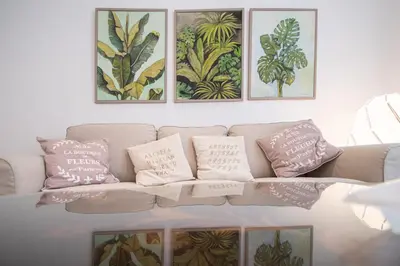 a living room with a couch with three pictures on the wall at Apartamento Garum in Cádiz