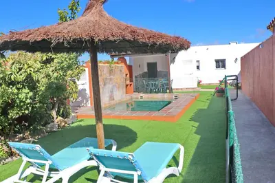 a yard with two chairs and an umbrella at Chalet Brenes Sol in Conil de la Frontera