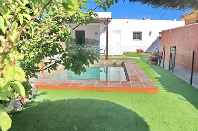 a backyard with a swimming pool and green grass at Chalet Brenes Sol in Conil de la Frontera
