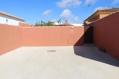 a courtyard of a house with an orange wall at Chalet Brenes Sol in Conil de la Frontera