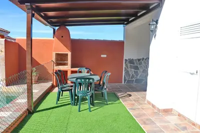 a patio with a table and chairs on a lawn at Chalet Brenes Sol in Conil de la Frontera