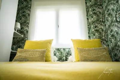 a bedroom with a bed with yellow pillows and a window at R&B Puerto Sherry Beach in El Puerto de Santa María