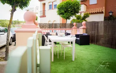a white table and chairs on a yard with green grass at R&B Puerto Sherry Beach in El Puerto de Santa María