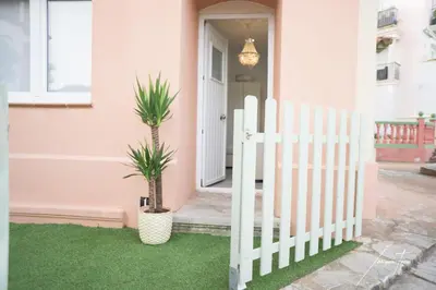 a white fence in front of a house with a palm tree at R&B Puerto Sherry Beach in El Puerto de Santa María
