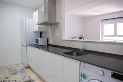 a white kitchen with a sink and a refrigerator at El mirador de Ancha in Cádiz
