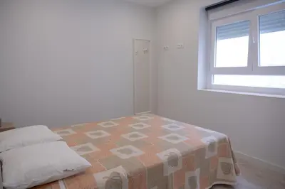 a white bedroom with a bed and a window at El mirador de Ancha in Cádiz
