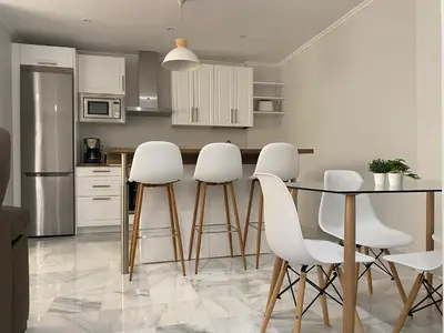 a kitchen with a table and white stools at Cartujano City Center Apartment in Jerez de la Frontera