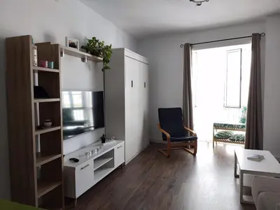 a living room with a television and a chair at Apartamento La Paraíta in Chiclana de la Frontera
